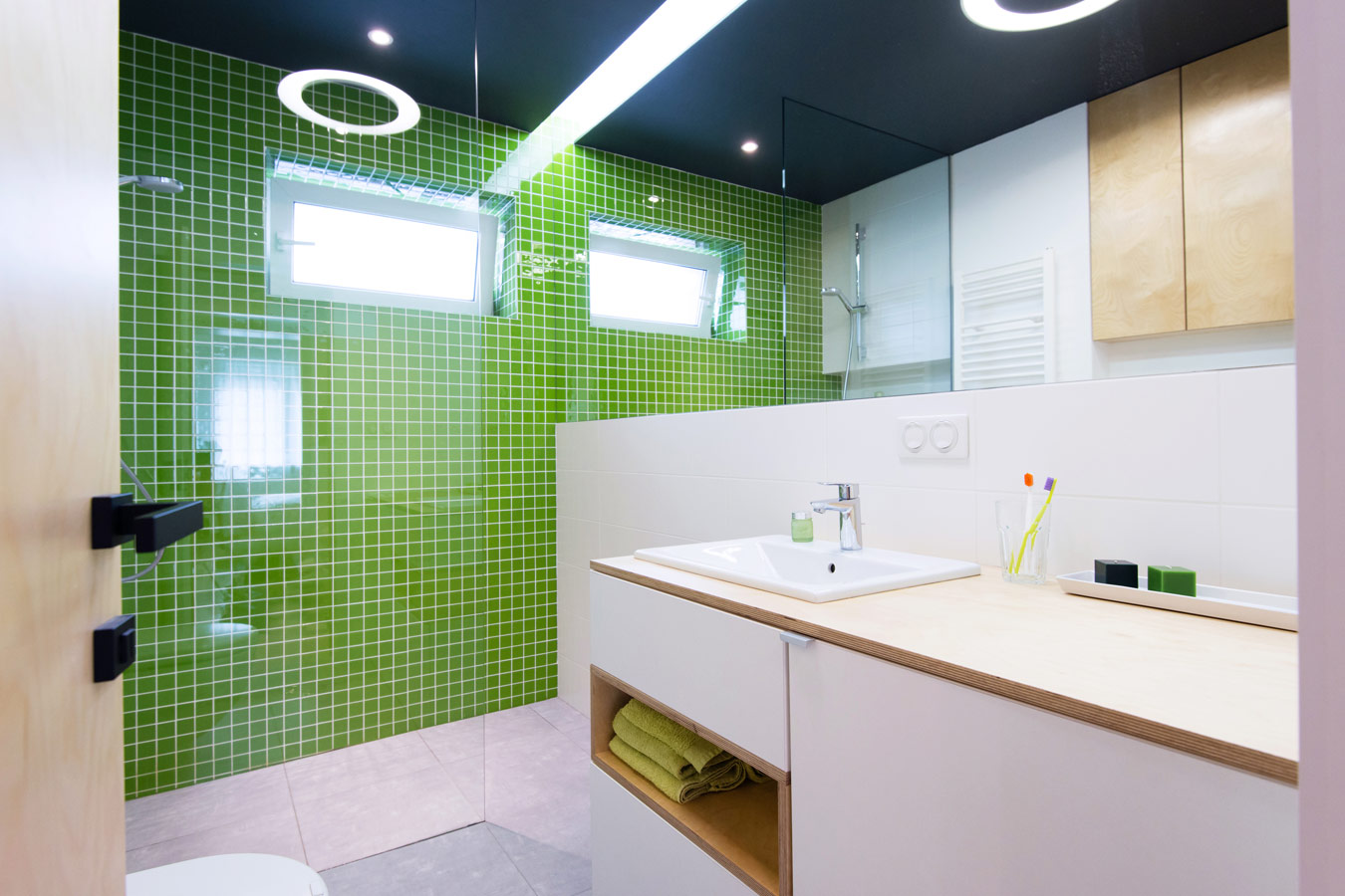 Badkamer met groene accentmuur in mozaiek tegels - glazen douchewand